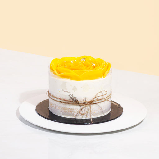 Vegan cake frosted with non-dairy cream, topped with a mango rose