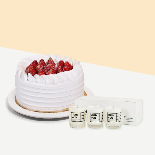 Cake coated with cream, topped with fresh strawberries with a bundle of scented candles of three