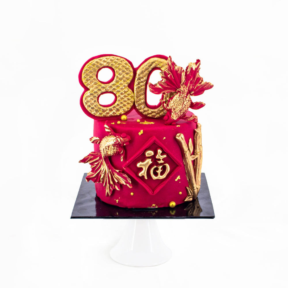 Longevity cake decorated in red fondant, with detailed gold accents decorations