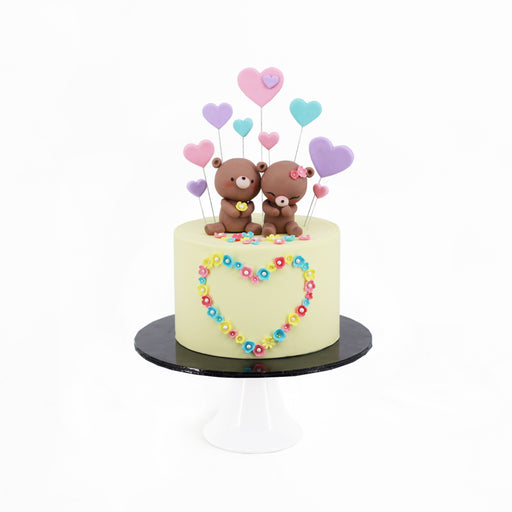 Cake decorated with colorful cream petals, with a bear couple made from fondant on top