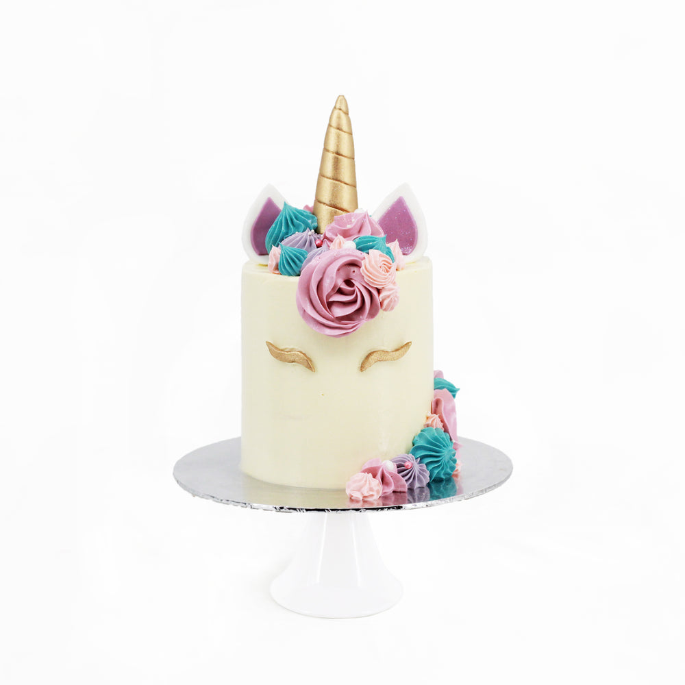 Unicorn cake with buttercream, decorated with hand piped cream, with golden eyelashes and horn