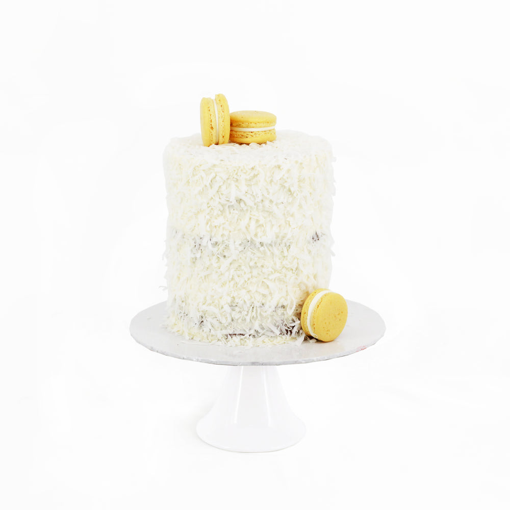 Cake covered in coconut shreds, topped with yellow macarons