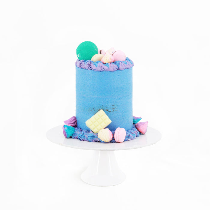 Blue buttercream cake with purple and blue cream swirls, decorated with colorful macarons