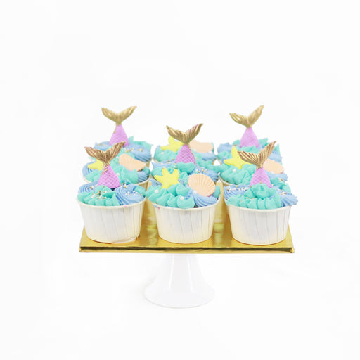 Mermaid themed cupcakes, topped with buttercream and fondant mermaid tail pieces
