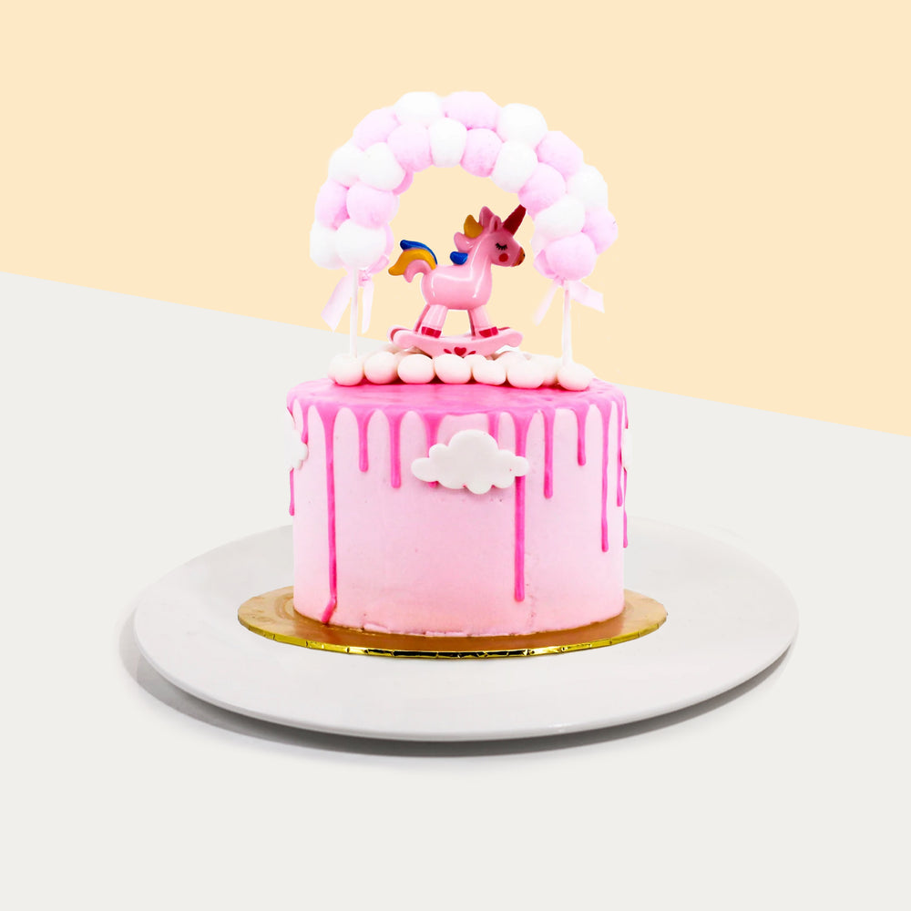 Pink baby girl themed cake, with a unicorn figurine on top