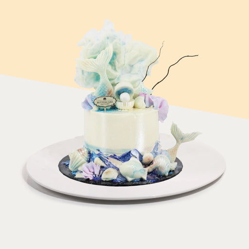 Butter cake frosted in shimmering buttercream, adorned with white chocolate sea shells, mermaid tails and fishes
