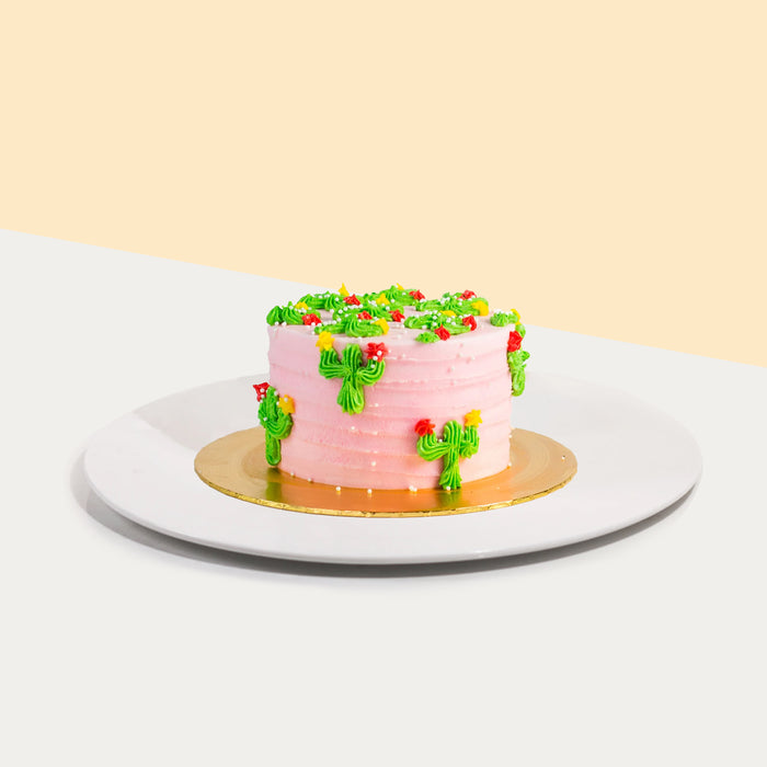 Pink buttercream cake with edible pearls, decorated with green cacti
