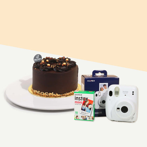 Chocolate cake topped off with edible pearls, beside a polaroid camera
