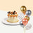 Cake coated with cream and caramel drizzle, garnished with chocolates and caramel popcorn with a bundle of balloons