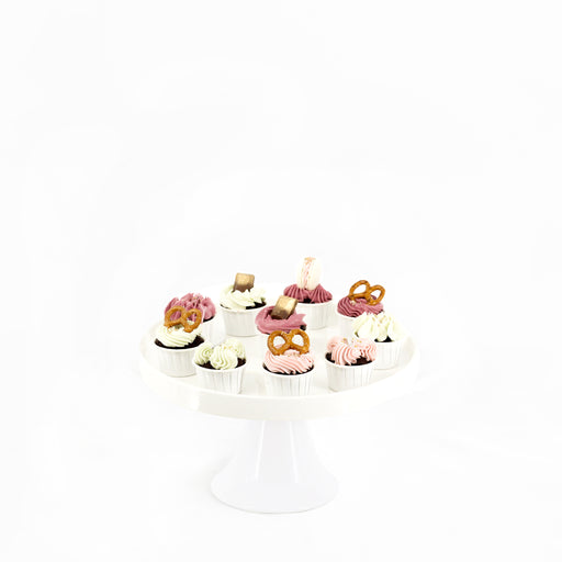 Cupcakes topped with a variety of white, pink and dark pink buttercream, and pretzels and macarons
