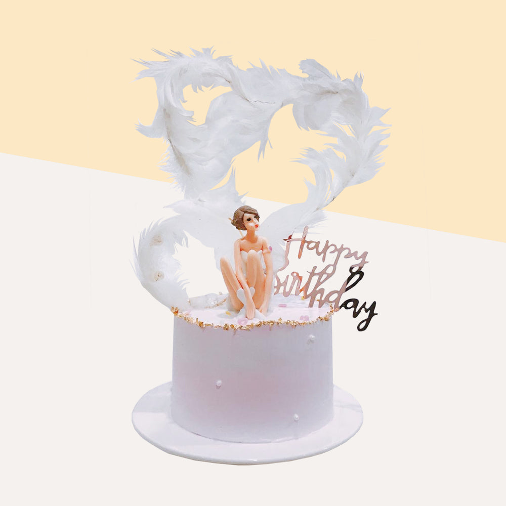 Chiffon cake with layers filled with fresh cream and fruits, topped with a lady figurine and white feather heart