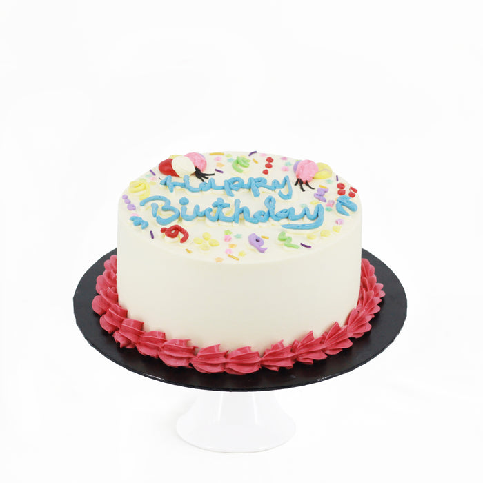 Buttercream cake with colorful decorations, and hand piped happy birthday on top