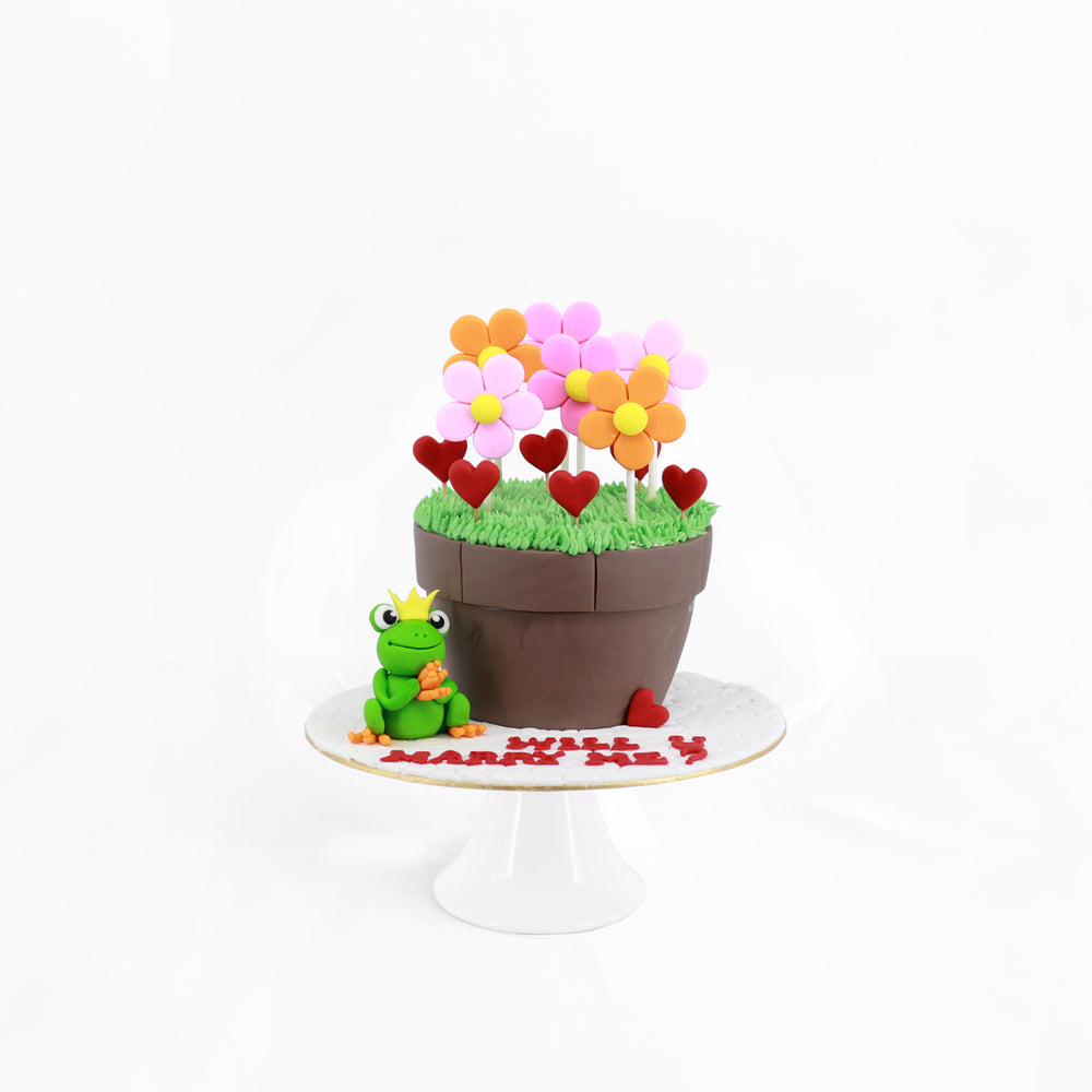 Fondant flower pot with fondant flowers, along with a fondant frog prince cake
