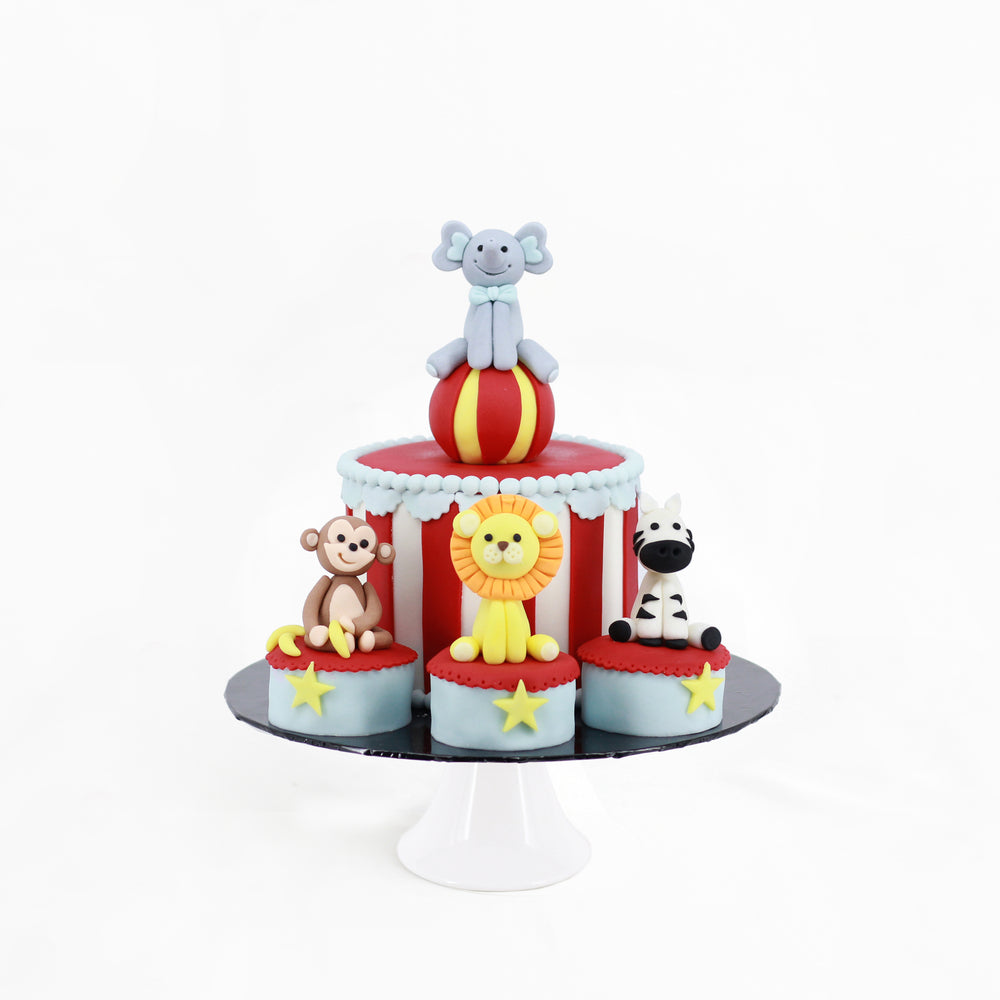 Circus themed cake decorated with fondant animals of elephant, monkey, lion and zebra