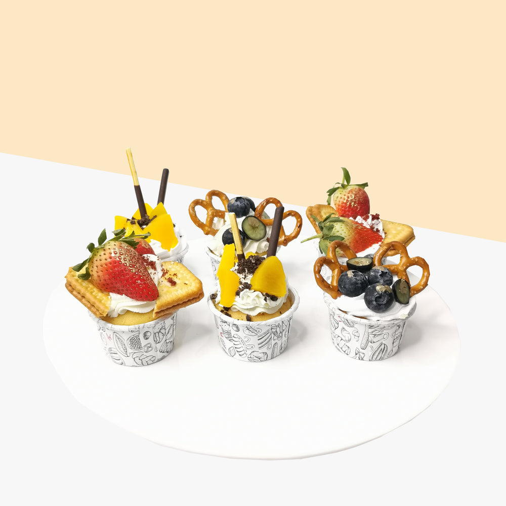 Cupcakes with fresh cream, fruits, pretzels and chocolate sticks