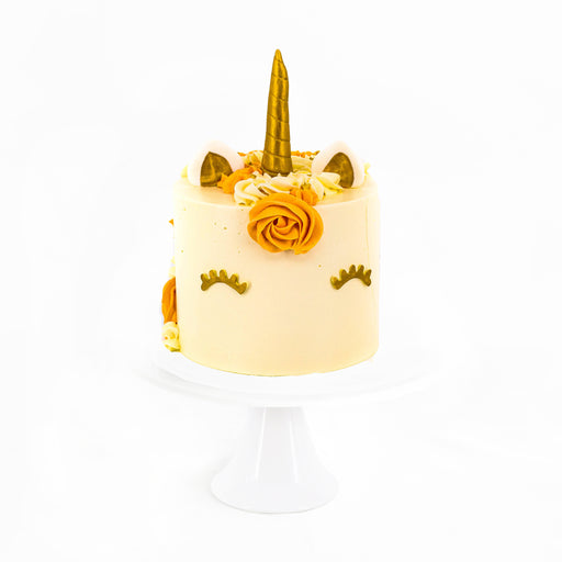 Golden unicorn cake with lashes, ears and a horn