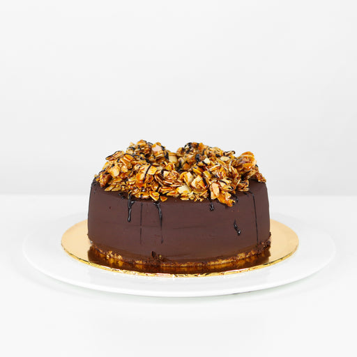 Banana cake frosted with chocolate, topped with salted almond brittles and dehydrated bananas
