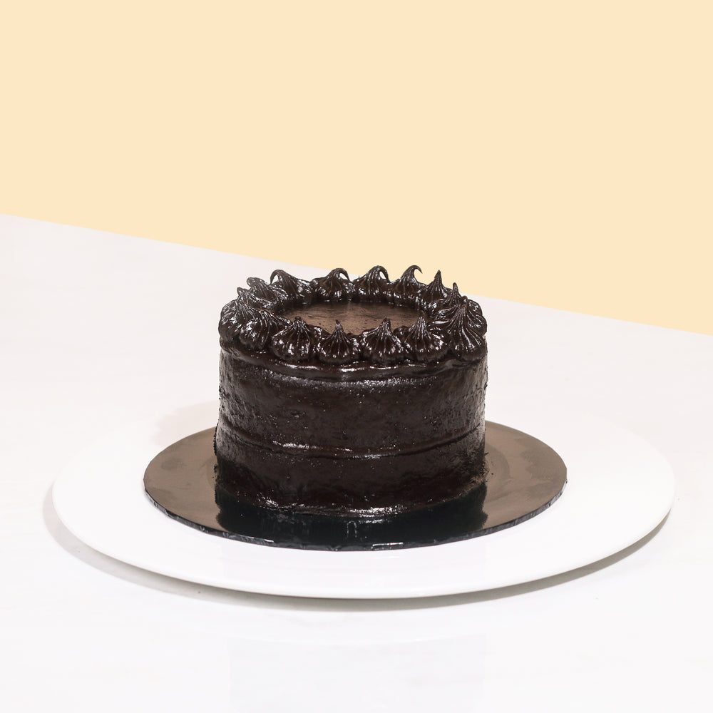 Mini chocolate cake coated head to toe with smooth chocolate cream, decorated with chocolate swirls