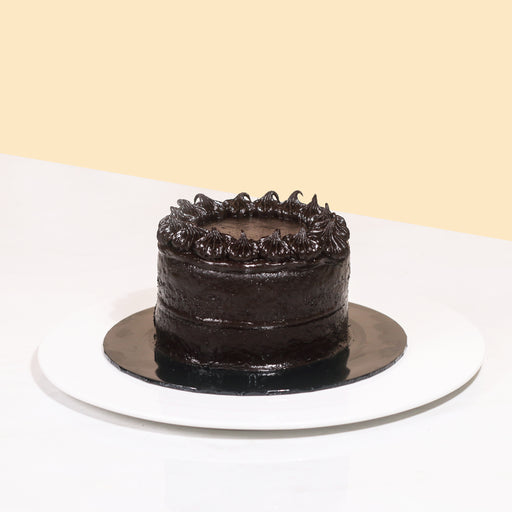 Mini chocolate cake coated head to toe with smooth chocolate cream, decorated with chocolate swirls
