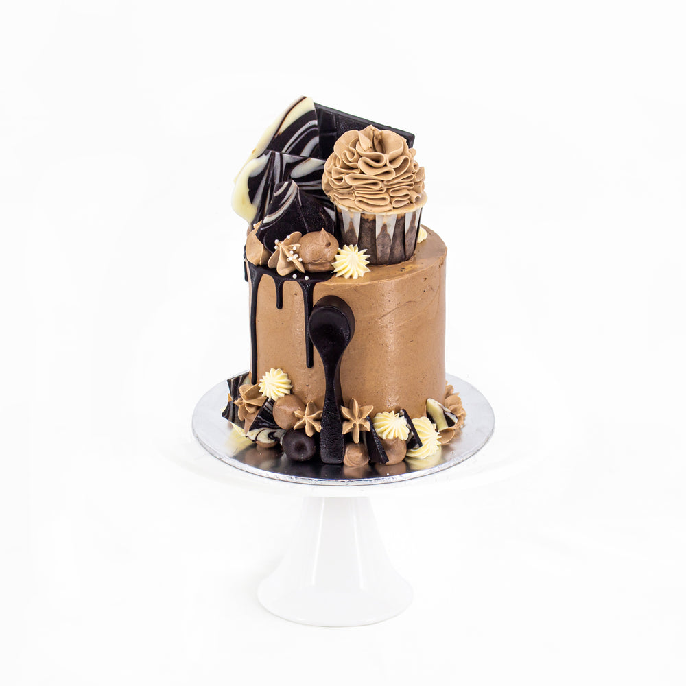 Chocolate and vanilla cake, decorated with chocolate shards and cupcake on top