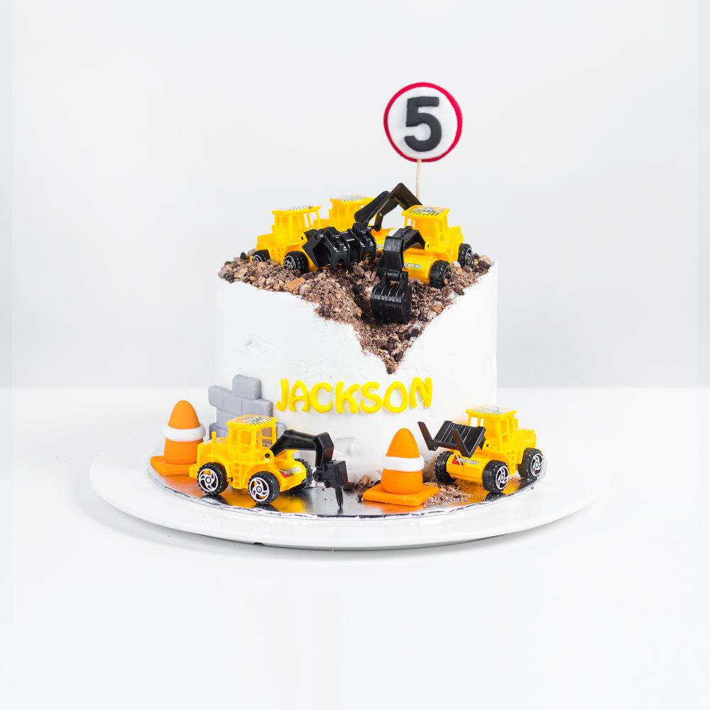 Construction themed cake with toy construction vehicles and fondant safety cones