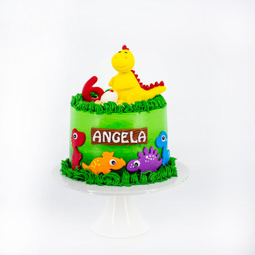 Dinosaur themed cake, with colorful dinosaurs and green grass buttercream