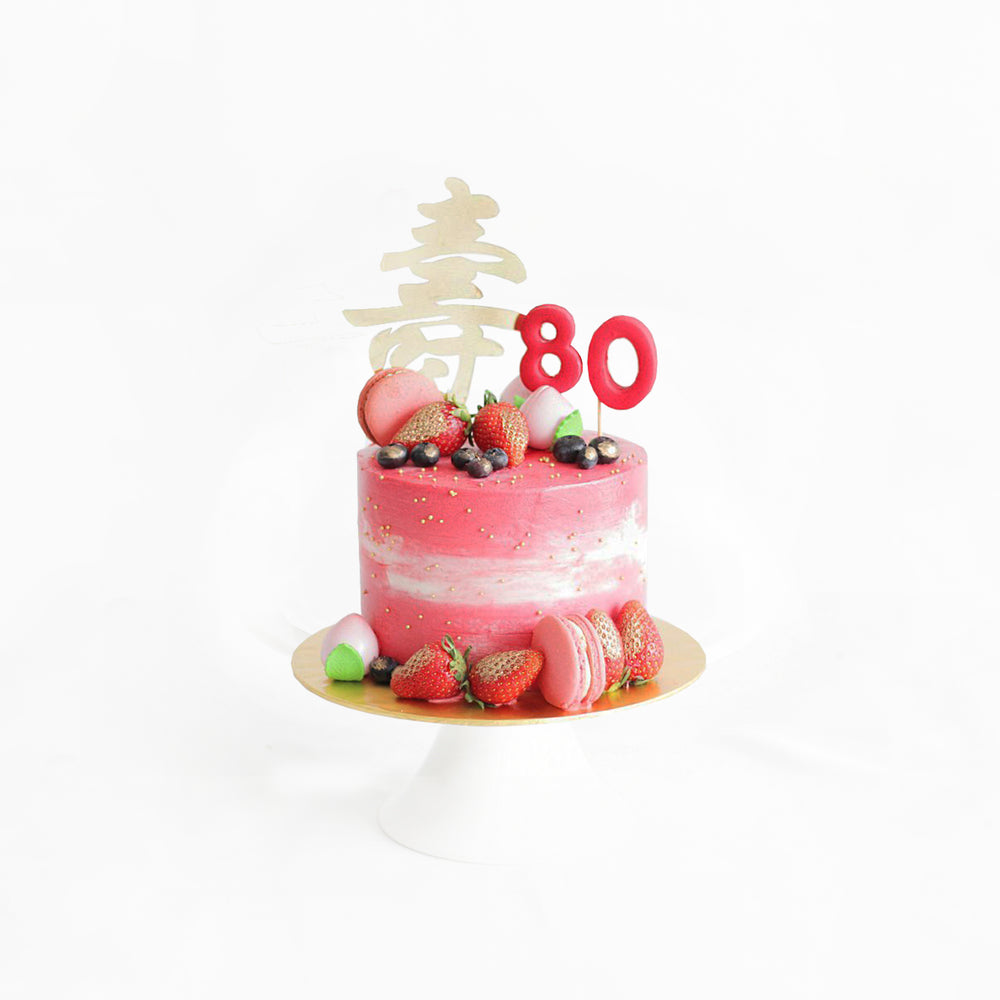 Pink prosperity cake with 寿 cake topper, strawberries, blueberries and macarons