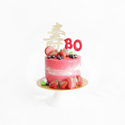 Pink prosperity cake with 寿 cake topper, strawberries, blueberries and macarons