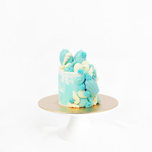 Sea themed cake with blue and white decorations, with edible seashells