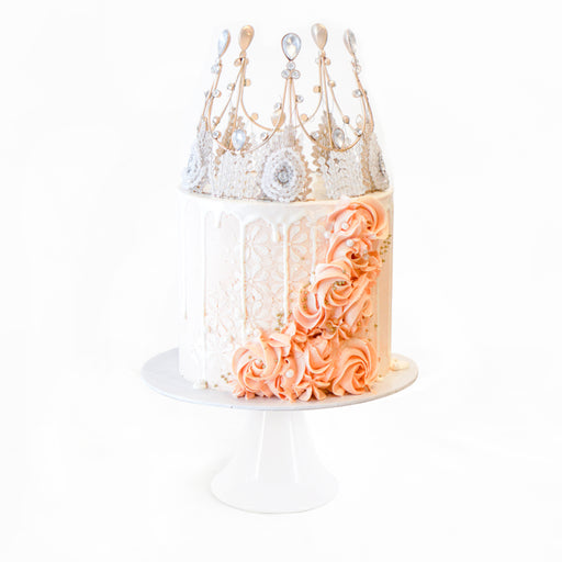 Elegant cake decorated with pink cream swirls, and a crown on top