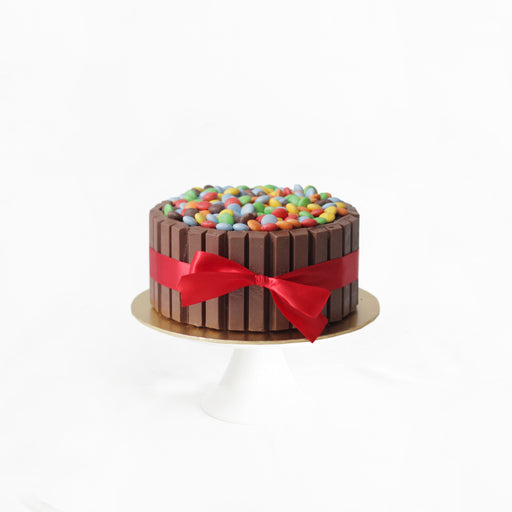 Cake fenced in with KitKats, topped with colorful chocolate buttons