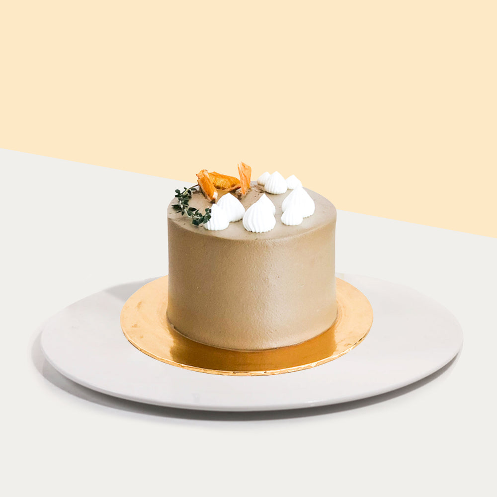 Coffee buttercream covered cake, topped with white cream spirals, thyme and dried orange slices
