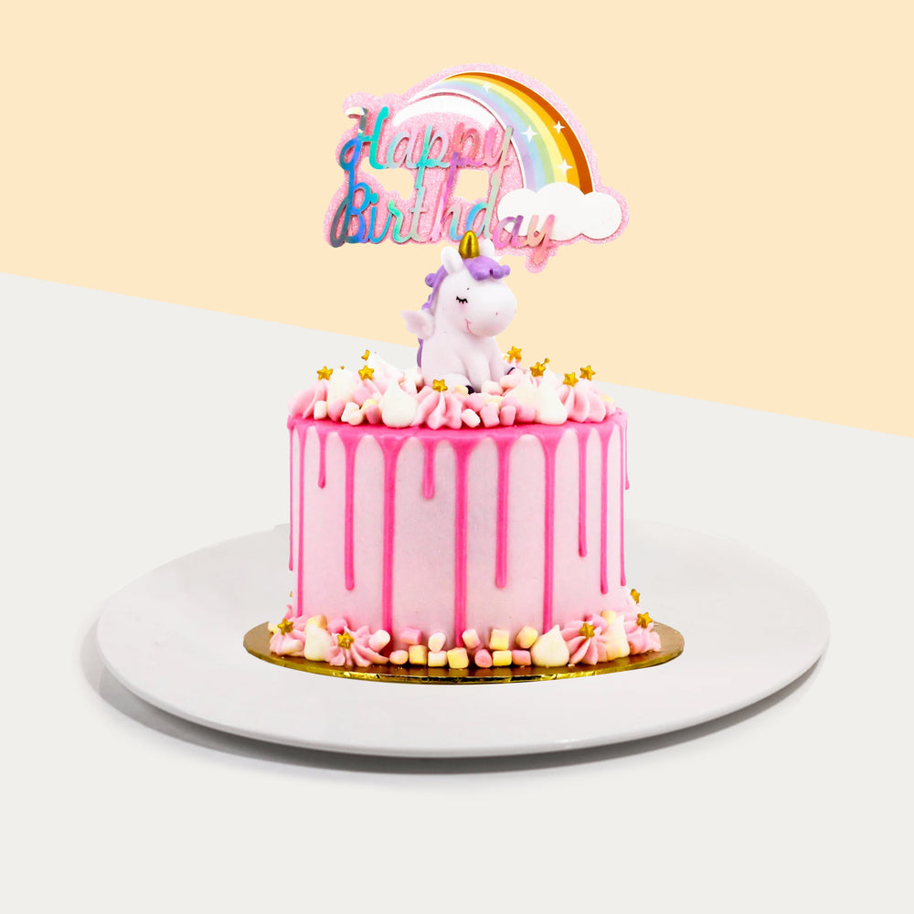 Pink buttercream frosted cake, with pink chocolate drizzle and a unicorn figurine on top