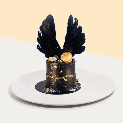 Black buttercream cake with gold accents, decorated with black wings