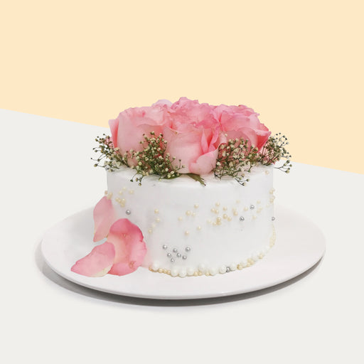 White buttercream cake with edible pearls, topped with fresh roses and baby breath