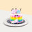 Rainbow themed cake with a unicorn taking a bite from the cake