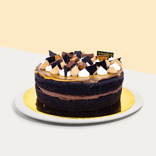 Chocolate cake topped with snickers, chocolate slices and a layer of caramel coat