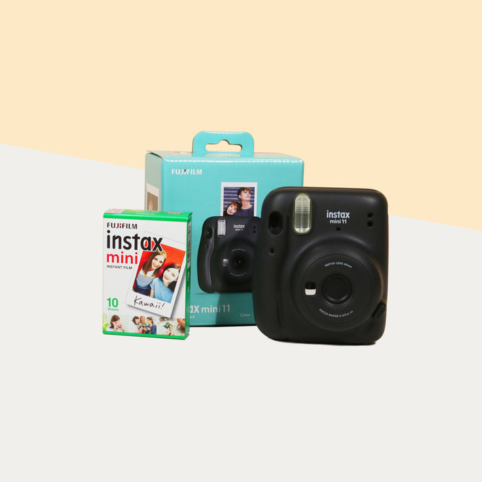 Instax Mini 11 Camera (Charcoal grey) with the retail box, beside a box of film
