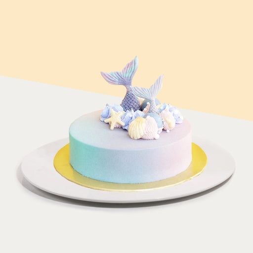 Ice cream cake in a teal to pink gradient, topped with edible white chocolate pieces