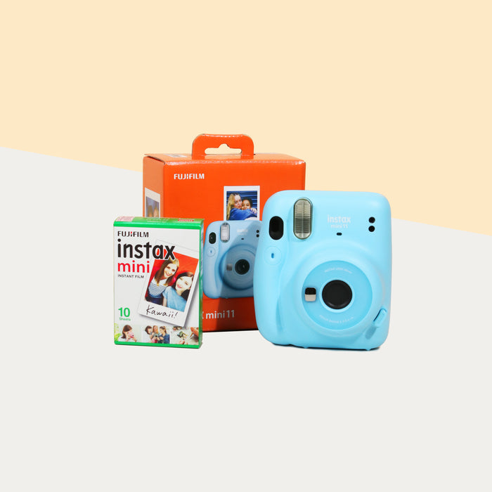 Instax Mini 11 Camera (Sky blue) with the retail box, beside a box of film