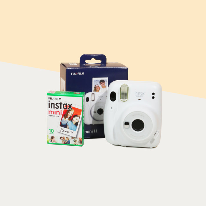 Instax Mini 11 Camera (Ice white) with the retail box, beside a box of film