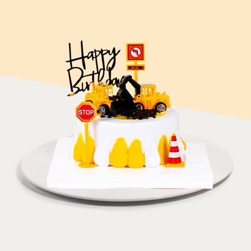 Construction themed cake, with construction vehicles, traffic cones and a stop sign.