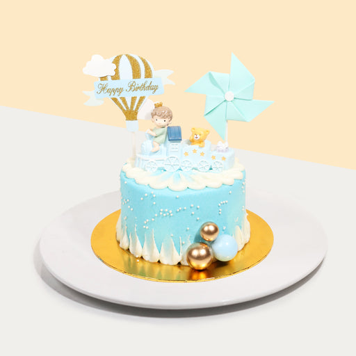 Butter cake frosted in blue buttercream, with a boy on a train figurine