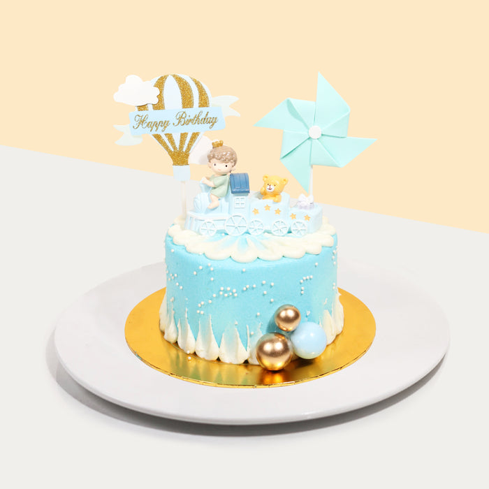 Butter cake frosted in blue buttercream, with a boy on a train figurine