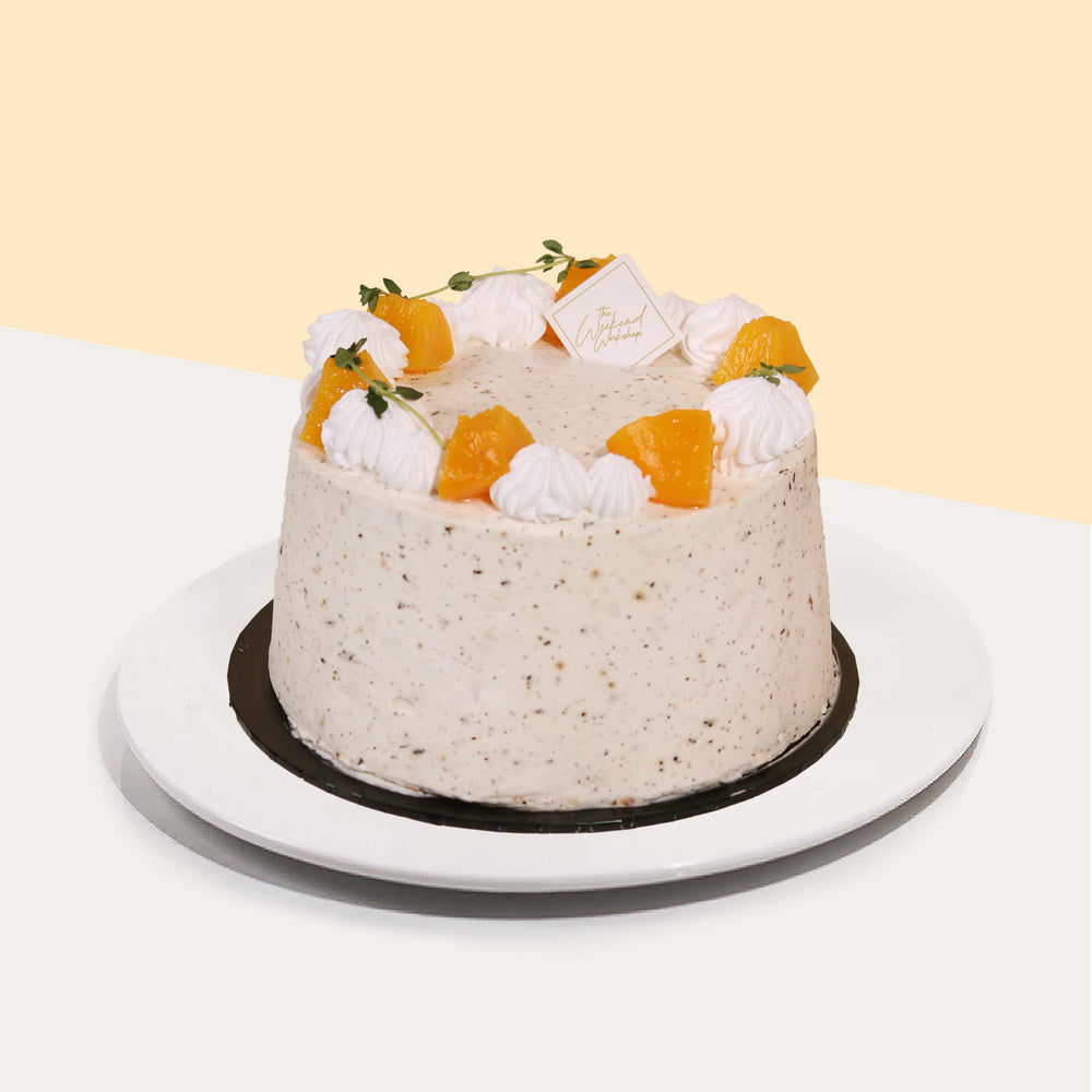 Peach short cake coated in hand-piped cream, topped with sliced peaches