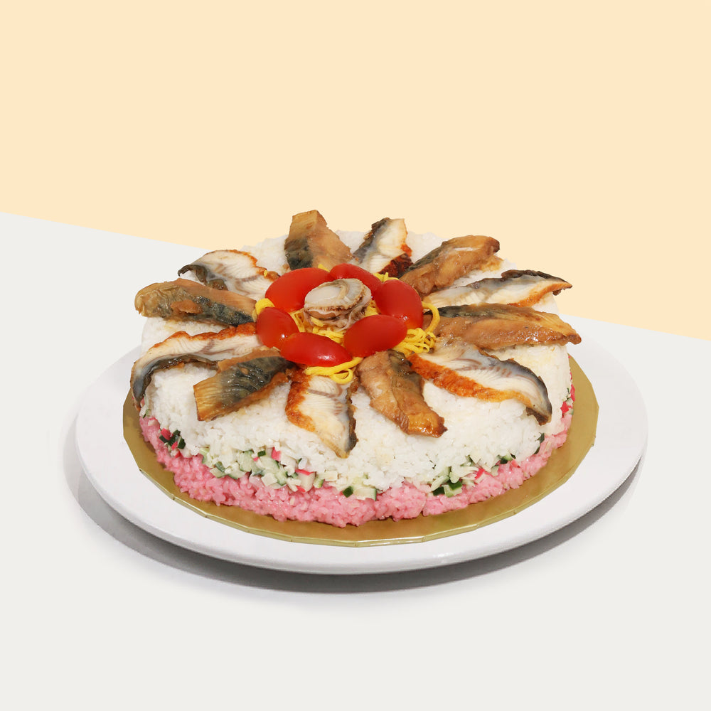 Round sushi cake topped with unagi, teriyaki saba, and a scallop