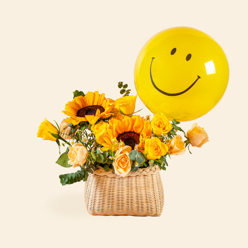 Flower basket with orange roses, yellow roses, sunflowers and a yellow smiley balloon
