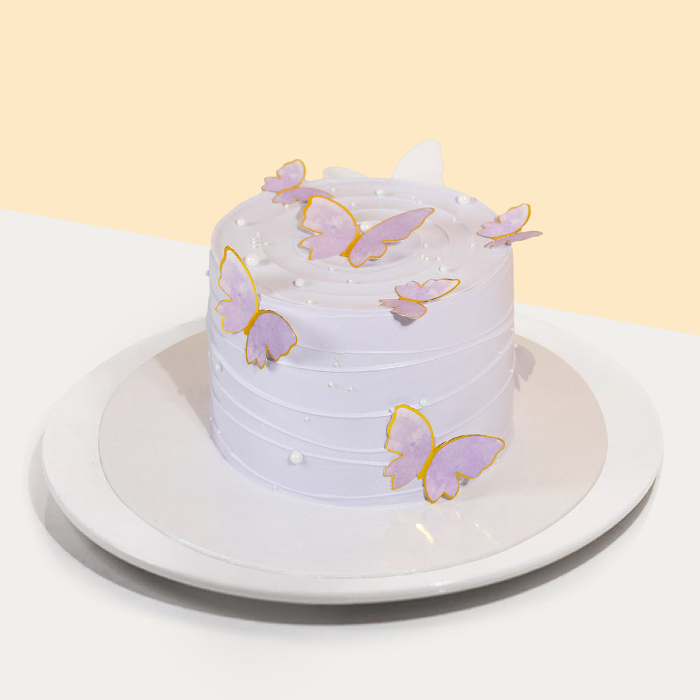 Chiffon cake frosted with violet buttercream, decorated with 2d violet butterflies and edible pearls