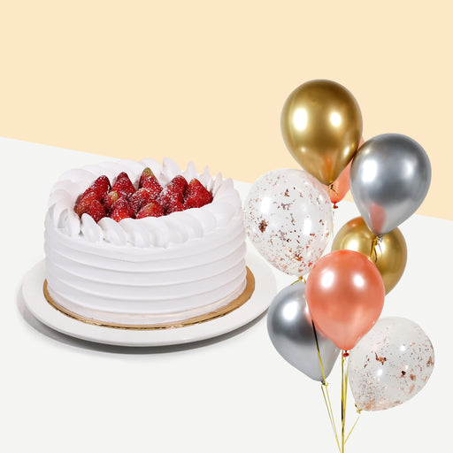 Cake coated with cream, topped with fresh strawberries with a bundle of balloons