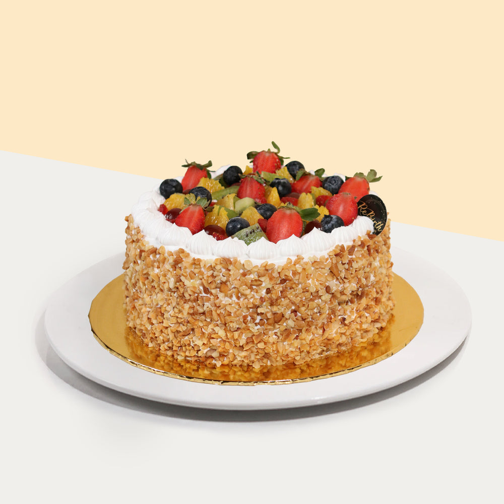 Fruit cake covered fresh cream and peanut chunks, topped with an abundant amount of fresh fruits